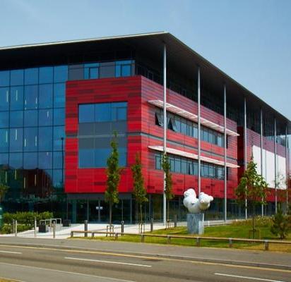 A modern red and glass square building on a sunny day
