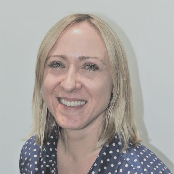 A profile picture of a person smiling at the camera. They have shoulder length hair and are wearing a spotty blouse