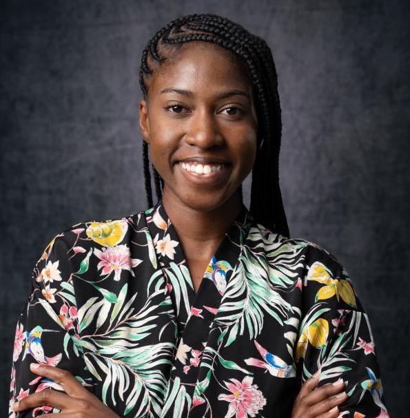 A person (Rianna Patterson) is wearing a floral shirt, smiling at the camera
