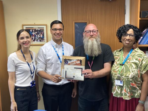 Four people smiling at the camera and holding a certificate