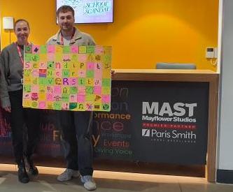 The team at Mayflower Studios hold up a Serendipity art display they created for Autism Acceptance Week 2024
