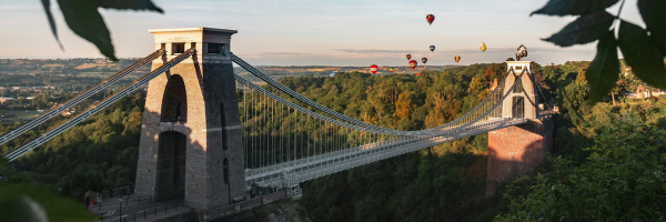 Clifton Suspension Bridge with hot air balloons flying above it.