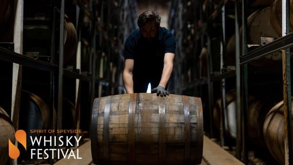 Man rolling barrel of whisky in warehouse