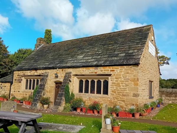 A sandstone historic building with lots of flower pots around the edge