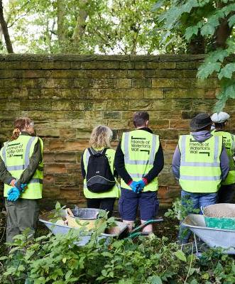 5 Friends of Waterton's Wall volunteers stood facing Waterton's Wall