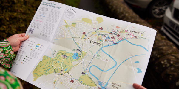 A person's hands holding a map of Stanley Heritage Trail