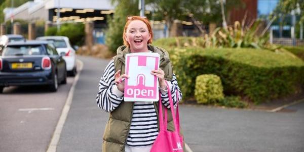 A person holding up an A4 'Open' sign with the Heritage Open Days logo