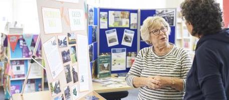 Two people in conversation next to a heritage display board