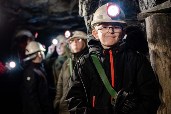 Children in a dark mine, wearing headlamp hard hats 