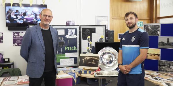 Two people stood in front of a display of Featherstone Rovers Foundation memorabilia