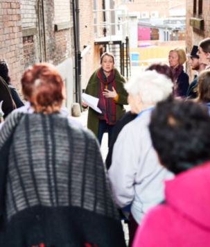 A person leading a heritage talk in an alley with a group of people