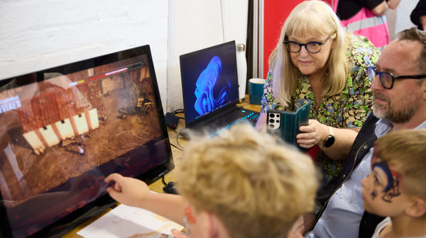 Children and adults engaging with the Roman Castleford Uncovered digital project on a touchscreen monitor