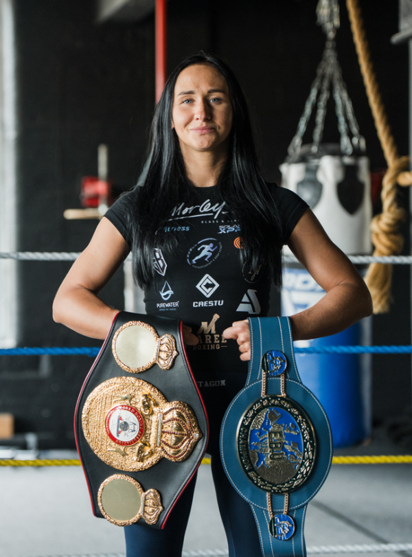A person holding belt awards in a boxing ring