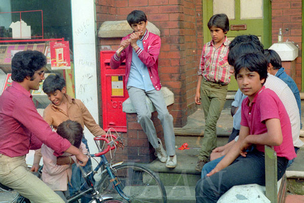 A group of South Asian boys and young men sitting outside a shop in Wakefield