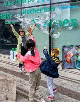 A person waving to two children