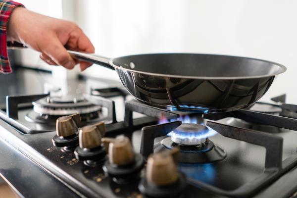 a fry pan resting on top of a lit gas hob cooker