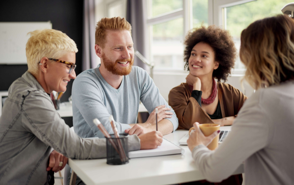 a group of people sat around a table taking notes and having a discussion