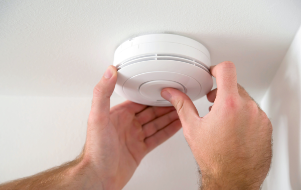 A smoke alarm fitted to a ceiling is being tested