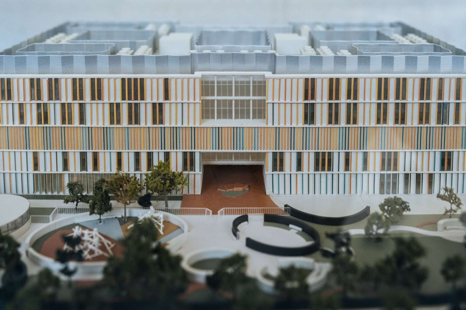 A model of Cambridge Children's hospital pictured from the back showing the large garden with lots of play equipment, grassa nd trees. The Building has lots of windows with colourful frames.