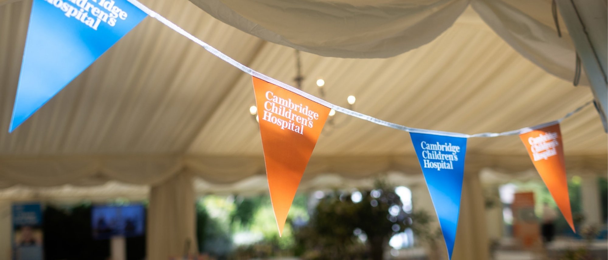 Orange and blue Cambridge Children's Hospital bunting strung across the entrance of a beautiful marquee 