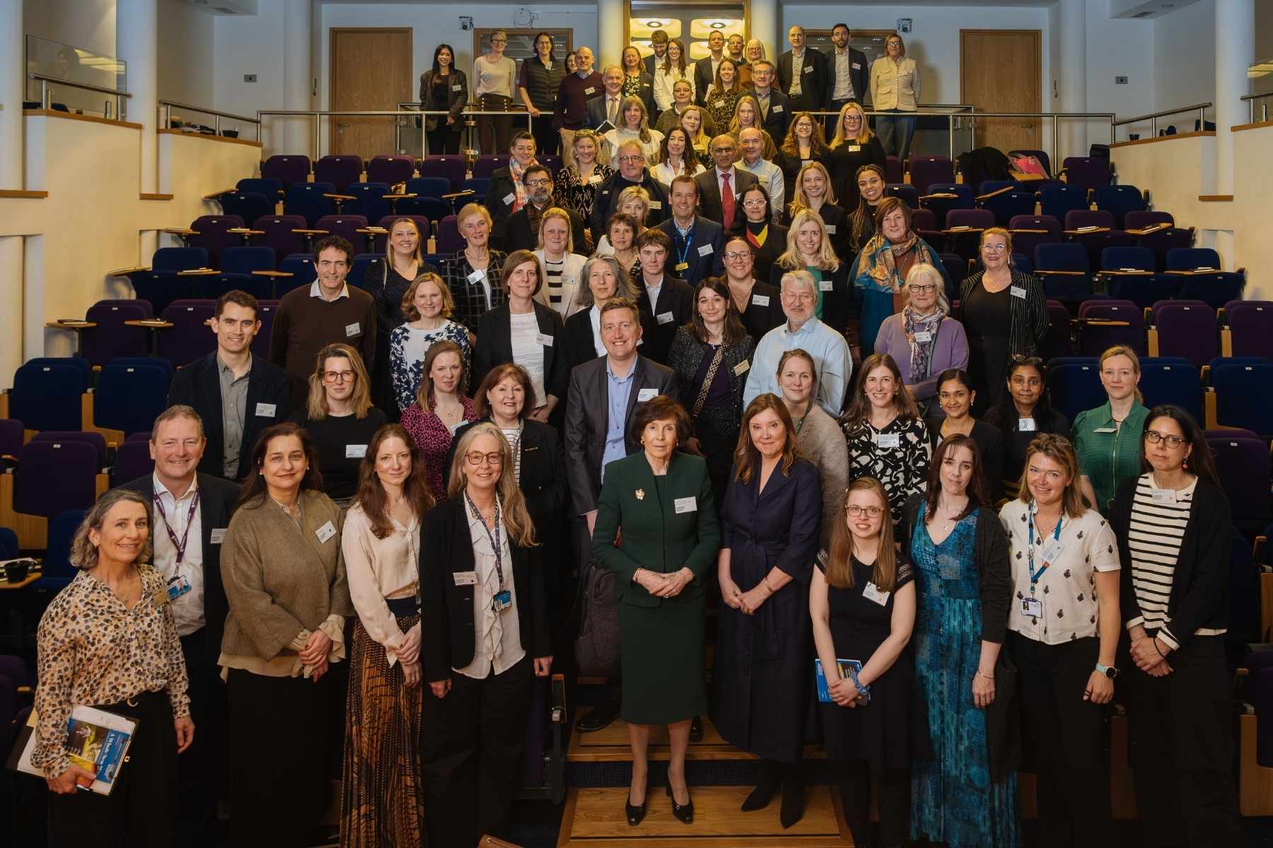A large group of people in a conference auditorium. They are all wearing smart clothes and are smiling for the camera.
