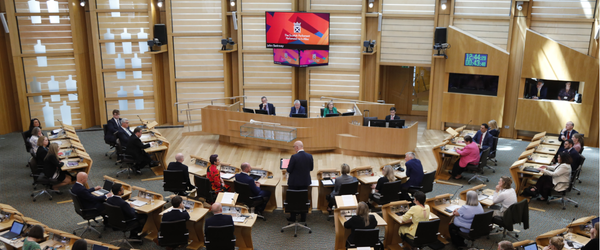 Am Pr&igrave;omh Mhinister, Iain Swinney BPA agus e a' toirt seachad &ograve;raid mun Phr&ograve;gram Riaghlaidh
